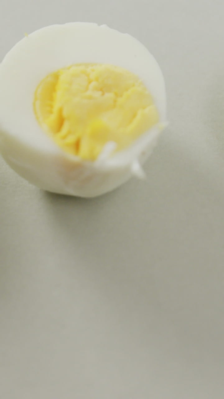 Video of close up of three halves of hard boiled eggs on grey background