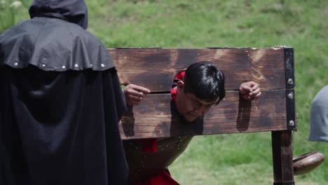 historical reenactment of a man in stocks with a cloaked figure