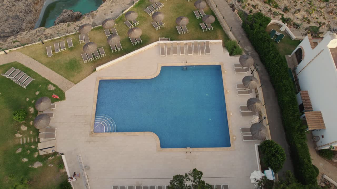Luftbåren stigende udsigt over et feriested på Mallorca med en klar blå pool og liggestole.