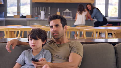 Father-And-Son-Sitting-On-Sofa-In-Lounge-Watching-Television