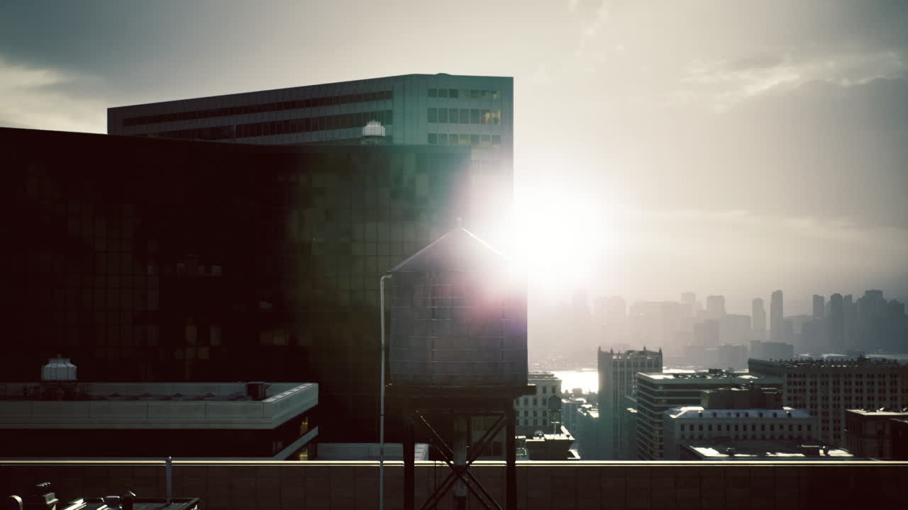 Un amanecer brillante siluetea una torre de agua industrial contra la neblina de la ciudad.