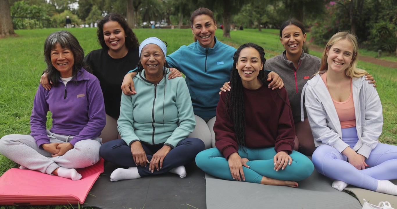 Diverse Group of Women Sitting Together on Yoga Mats in a Park