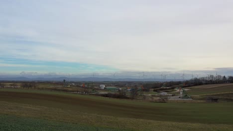 [DRONE]low-push-in-shot-while-tilting-up-of-oil-derricks-and-wind-turbines-in-the-background