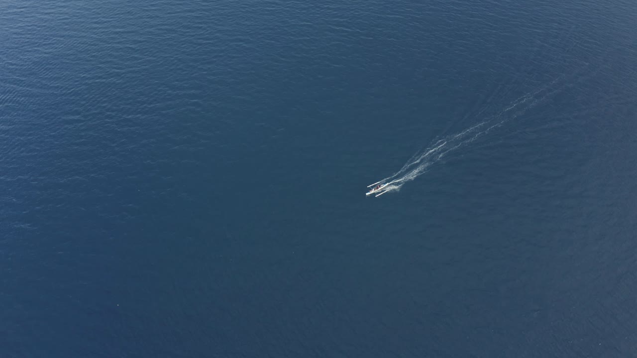 필리핀의 열대 섬에 있는 맑은 청록색 푸른 물 위에서 달리는 작은 어선의 놀라운 공중 영상 - 드론 샷