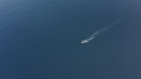 amazing aerial footage of a small running fishing boat on a crystal clear turquoise blue water on a tropical island in the philippines - drone shot