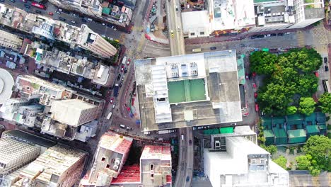 Traffic-passing-through-a-Car-park-building-in-downtown-Hong-Kong,-with-city-mega-buildings,-Aerial-view