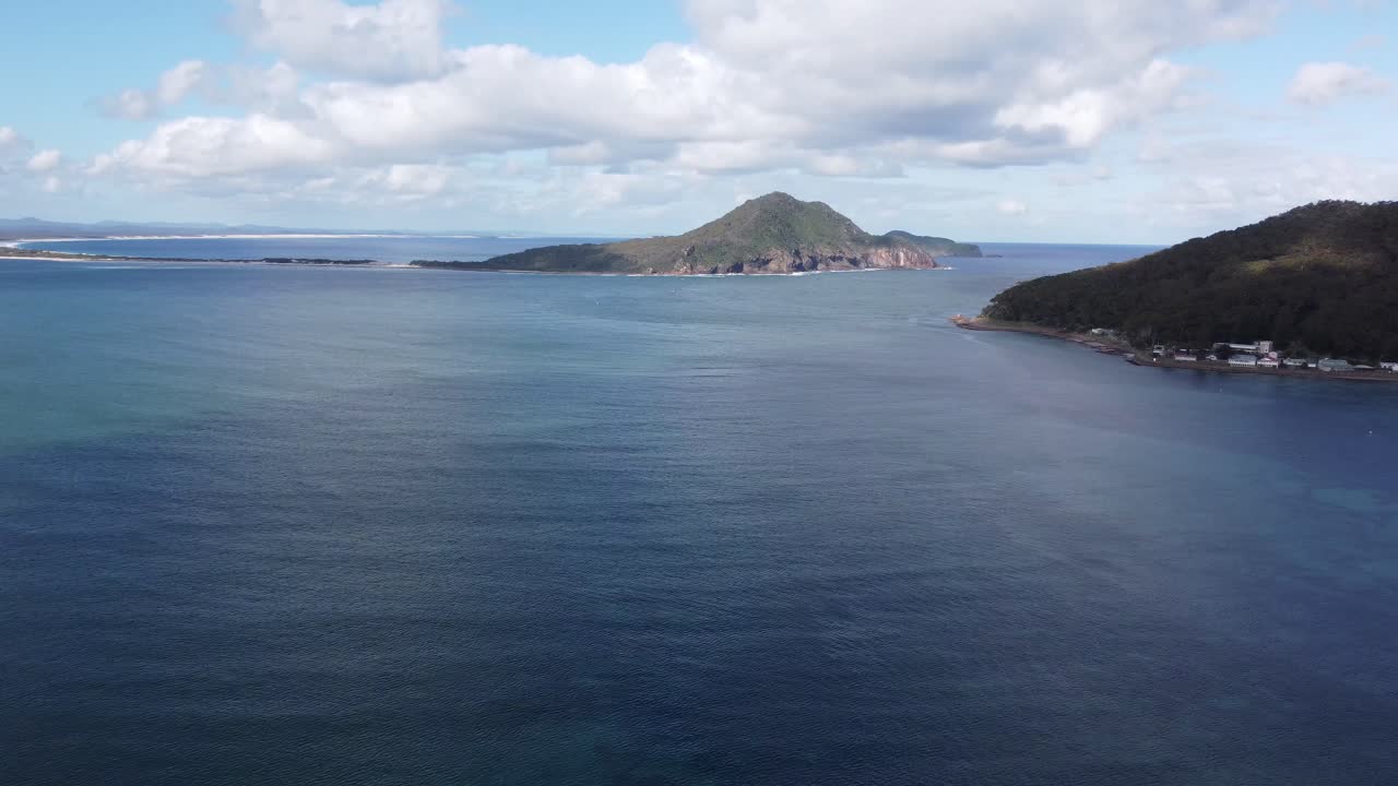 drone volando sobre el océano azul hacia una isla en australia