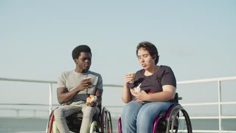 pareja feliz con discapacidad bebiendo café y comiendo pasteles