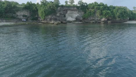 Low-altitude-dolly-drone-shot-of-polluted-water-filled-with-floating-trash-in-the-turqouise-tropical-water-of-Bali-Indonesia