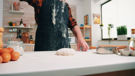 Close-up-of-man-sieving-flour-on-bread-dough