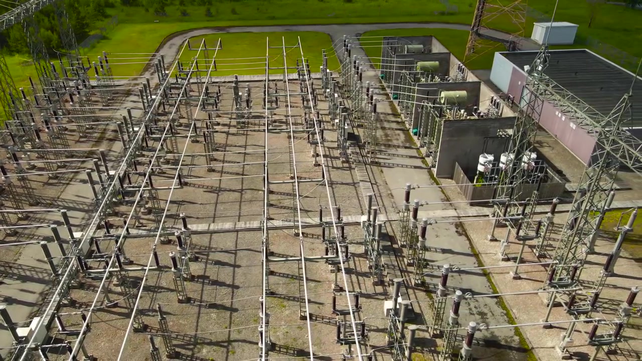 Hochspannungs-Umspannwerk mit Transformatoren, Isolatoren und Kabeln zur Stromverteilung, eine Luftaufnahme, die das komplexe Stromnetz und die industrielle Infrastruktur zeigt.