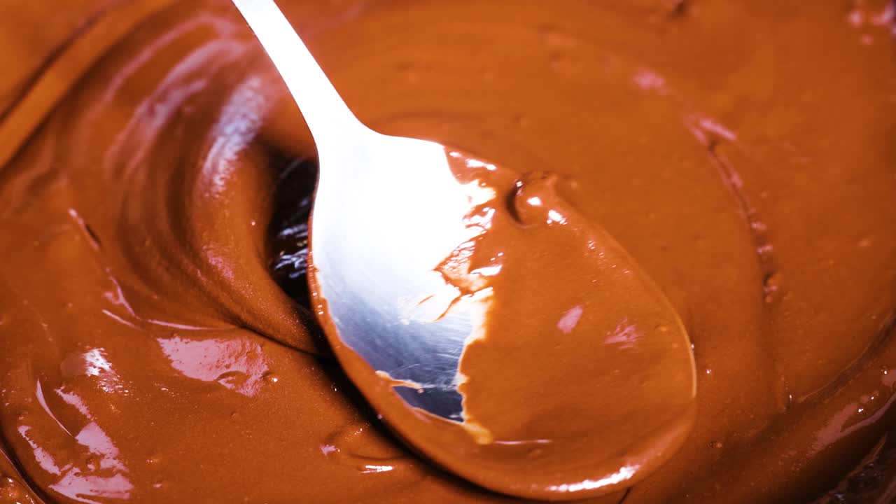 Cucchiaio che mescola cioccolato fuso e liscio in movimento