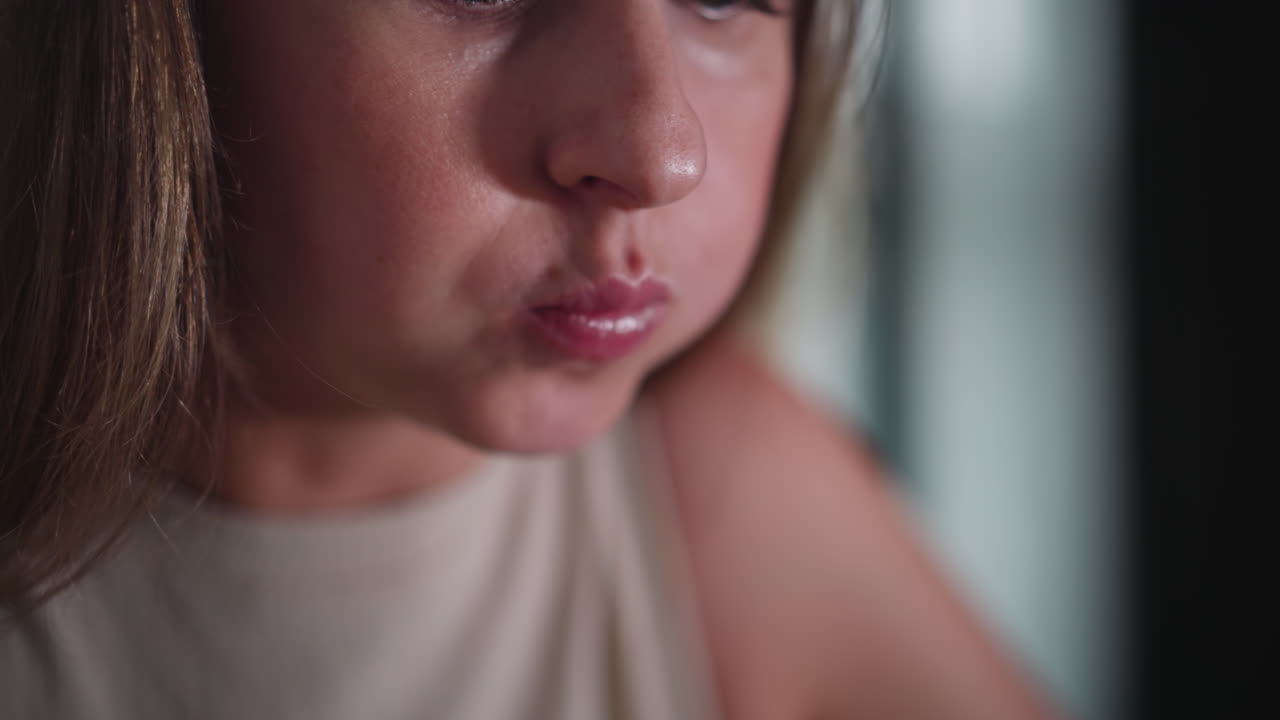 Close up of young white woman eating food using chopsticks, carefully lifting bite to lips, focused on meal, soft indoor lighting with gentle background blur