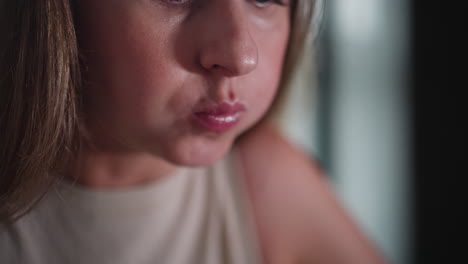 close up of young white woman eating food using chopsticks, carefully lifting bite to lips, focused on meal, soft indoor lighting with gentle background blur