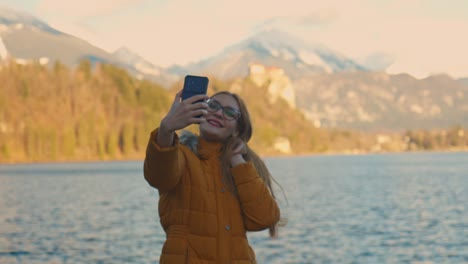 video en 4k de una hermosa joven caucásica tomando una foto selfie en un destino turístico muy famoso, bled, eslovenia.