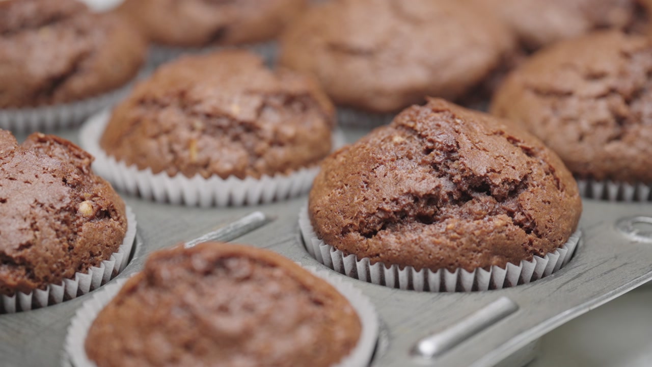 Fast push in close up of freshly baked chocolate muffins in tray with soft texture