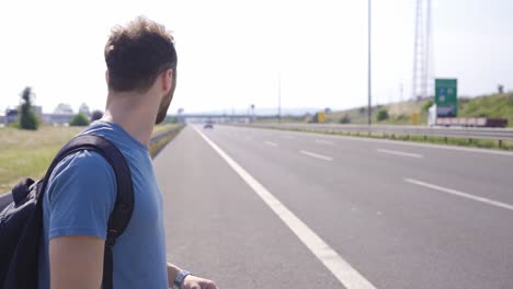 man hitchhiking by the highway.