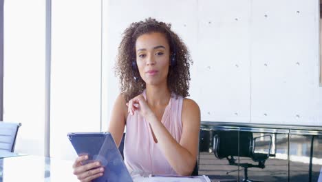 Young-mixed-race-businesswoman-talking-on-headphone-at-desk-in-office-4k