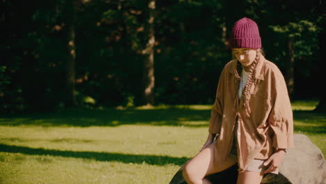 sad young woman sitting on rock at park