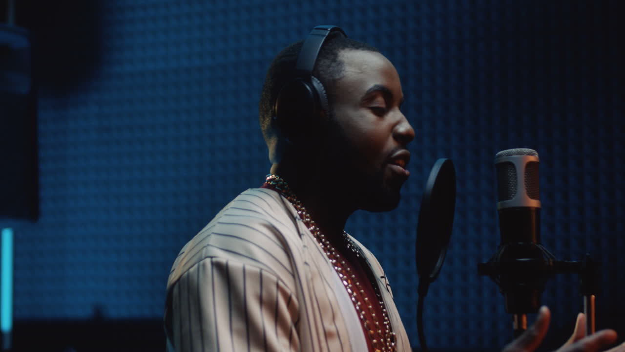 잘생긴 젊은 가수가 스튜디오에서 녹음하면서 마이크에 노래를 부른다