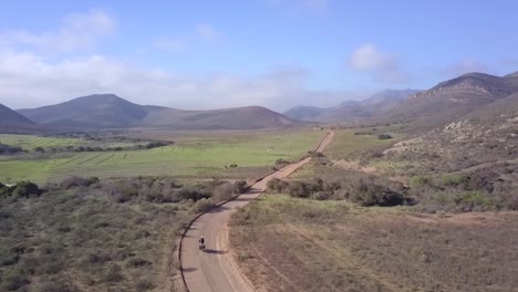 Aerial,-Motorcycle-on-country-road-in-mountain-valley-of-Baja-California,-Mexico