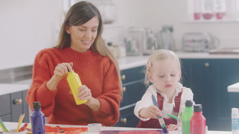 madre con hija en casa haciendo artesanía y pintando cuadros en la cocina