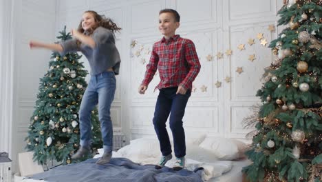 two smiling teens jumping bed in luxury house. cheerful kids having jump party