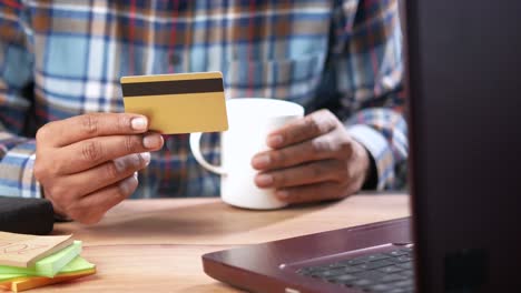 persona con una tarjeta de crédito y usando una computadora portátil