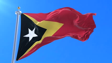 east timorese flag waving at wind with blue sky in slow, loop