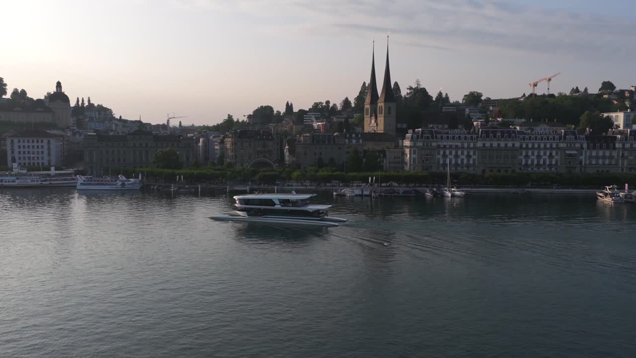 Sleek white boat navigating Lucerne lake with mountain backdrop in warm lighting