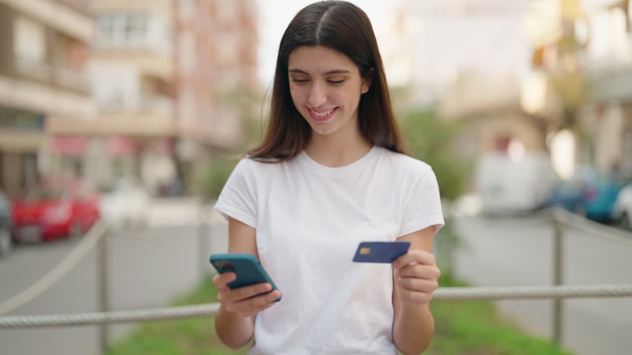 joven hispana hablando en el teléfono inteligente y usando tarjeta de crédito en la calle