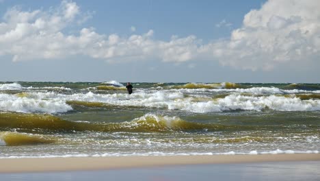 man on a kitesurfing board on high waves of baltic sea, poland.