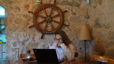 young blonde woman working from a stone house