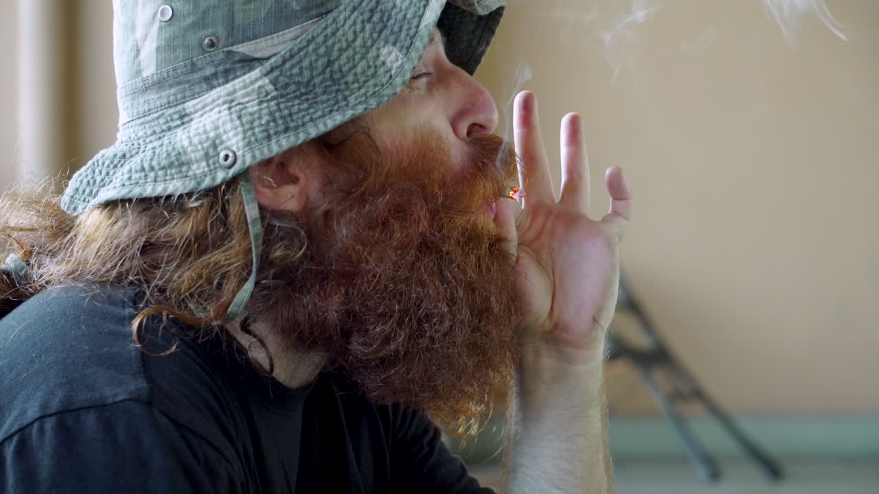 야외에서 마리화나를 피우고 부러진 벤치 근처에서 기침을 하는 노숙자