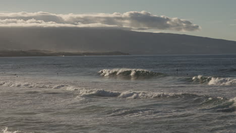 amplia vista de la gente surfeando en las olas por la costa de azores a la hora dorada