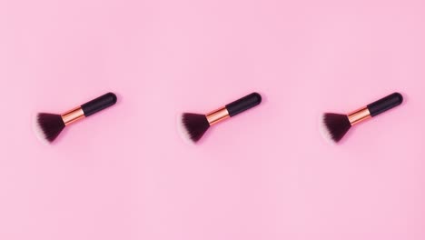 tres pinceles de maquillaje se mueven sobre un fondo rosado brillante. detenga el movimiento