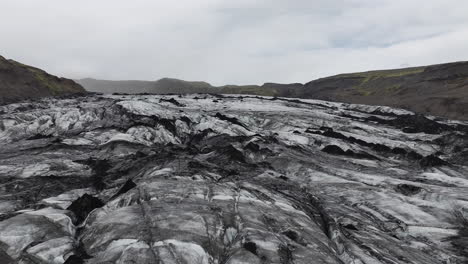 Flying-Above-Glacier,-Black-and-White-Ice-Cap-Under-Volcanic-Hills,-Iceland