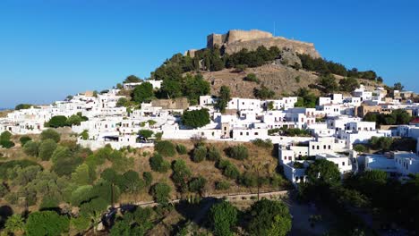 Acropolis-of-Lindos-in-Rhodes,-Greece-with-houses-and-Mediterranean-sea-during-the-day-filmed-with-the-drone