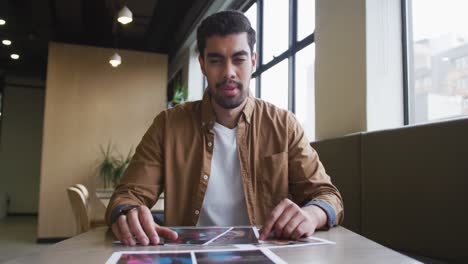 Mixed-race-businessman-having-a-video-chat-going-through-paperwork-in-a-modern-office