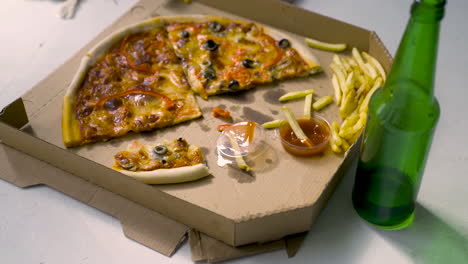 deliciosa pizza con aceitunas negras y pimientos rojos, papas fritas con salsa de tomate y botella de cerveza vacía