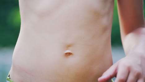 Close-up stomach of a boy. Young boy pulls his belly and shows ribs on his naked body.