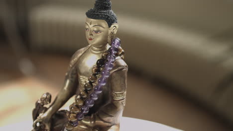 4k slider shot of golden buddha statue with prayer beads shallow depth of field