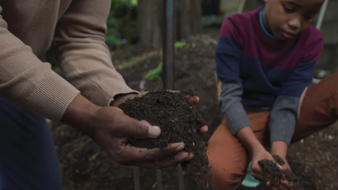Feliz homem afro-americano idoso com seu neto plantando no jardim