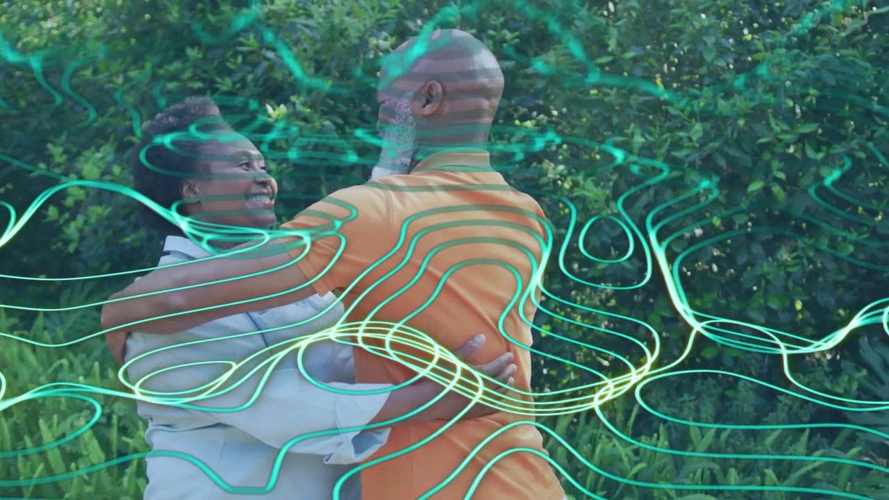 Couple showing love at hedge, woman reaching up, turning, teal waves sweeping across couple for ads