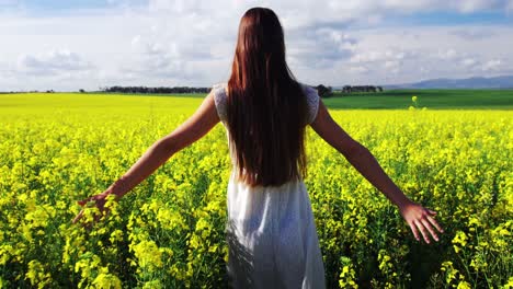 woman touching flowers while walking in field