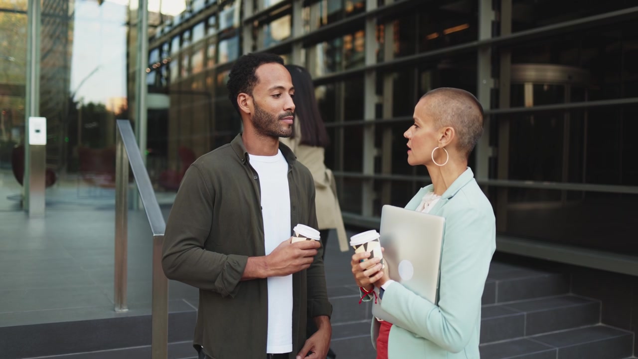 Colleagues Talking and Holding Coffee Outside Modern Office Building