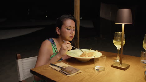 woman savoring a gourmet dinner under the warm light of the resort