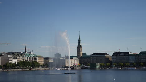 people enjoy rowing and paddling at binnenalter lake in hamburg, germany at sunny day. alster fountain and swanin the picture.
