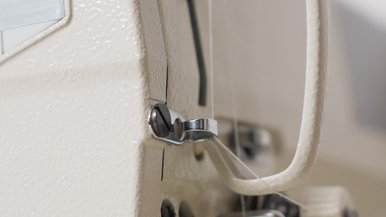 Close up of thread guide on sewing machine, showcasing clamp mechanism, offering stable tension, ensuring accurate stitches, highlighting minimal environment, mechanical detail, crisp lighting