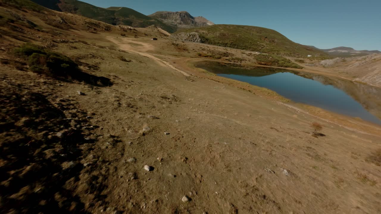 FPV aerial view of an isolated lagoon in alpine terrain